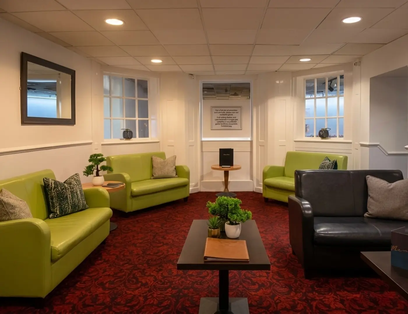 Torpark Hotel guest lounge with green armchairs, dark leather sofa and patterned carpet