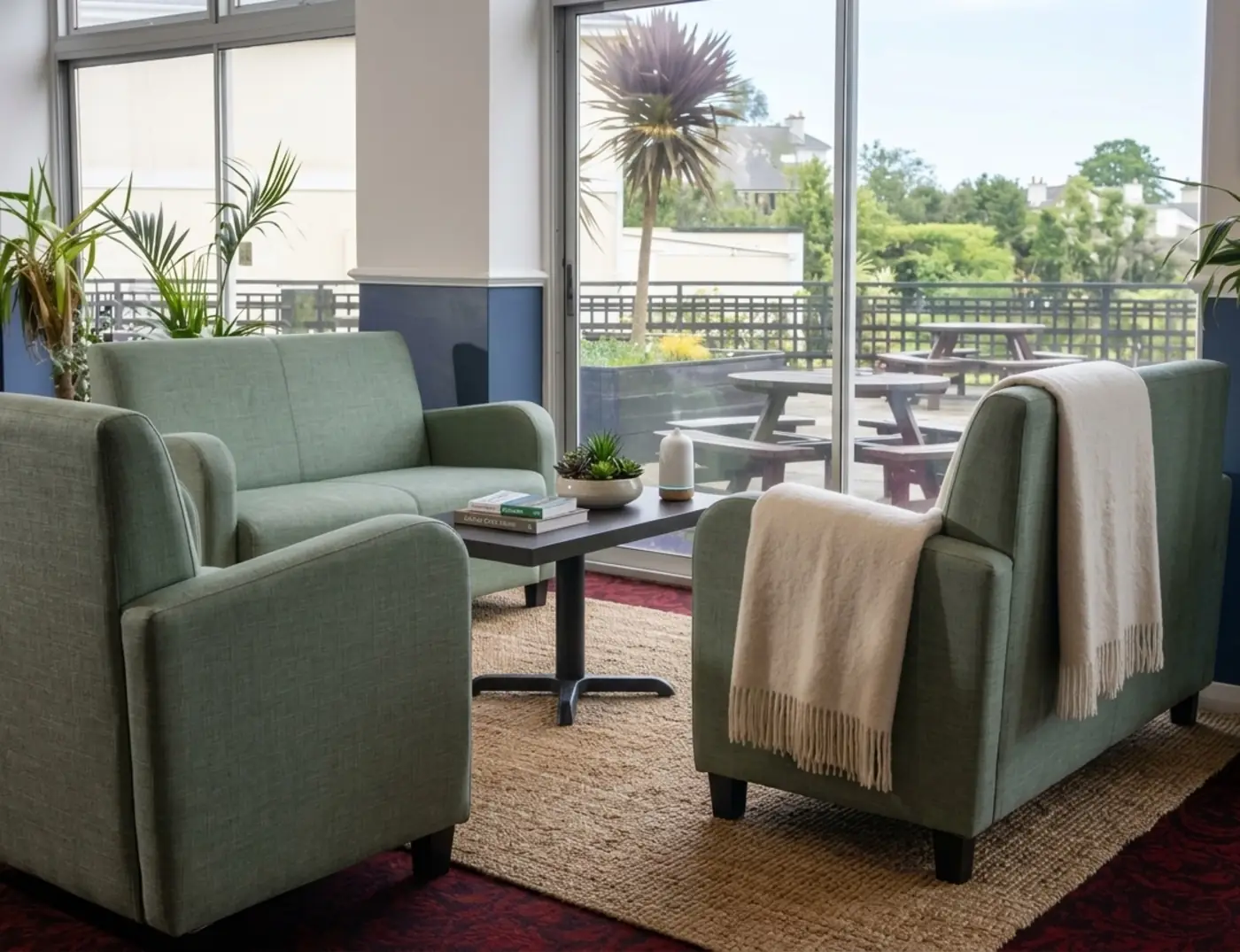 Torpark Hotel guest lounge with green armchairs, coffee table and view of the terrace garden